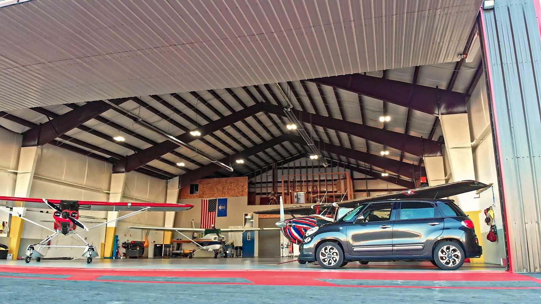 custom multi-aircraft hangar by Great Western Buildings in Hayden, Idaho shot from outside in with multiple aircraft and a vehicle inside