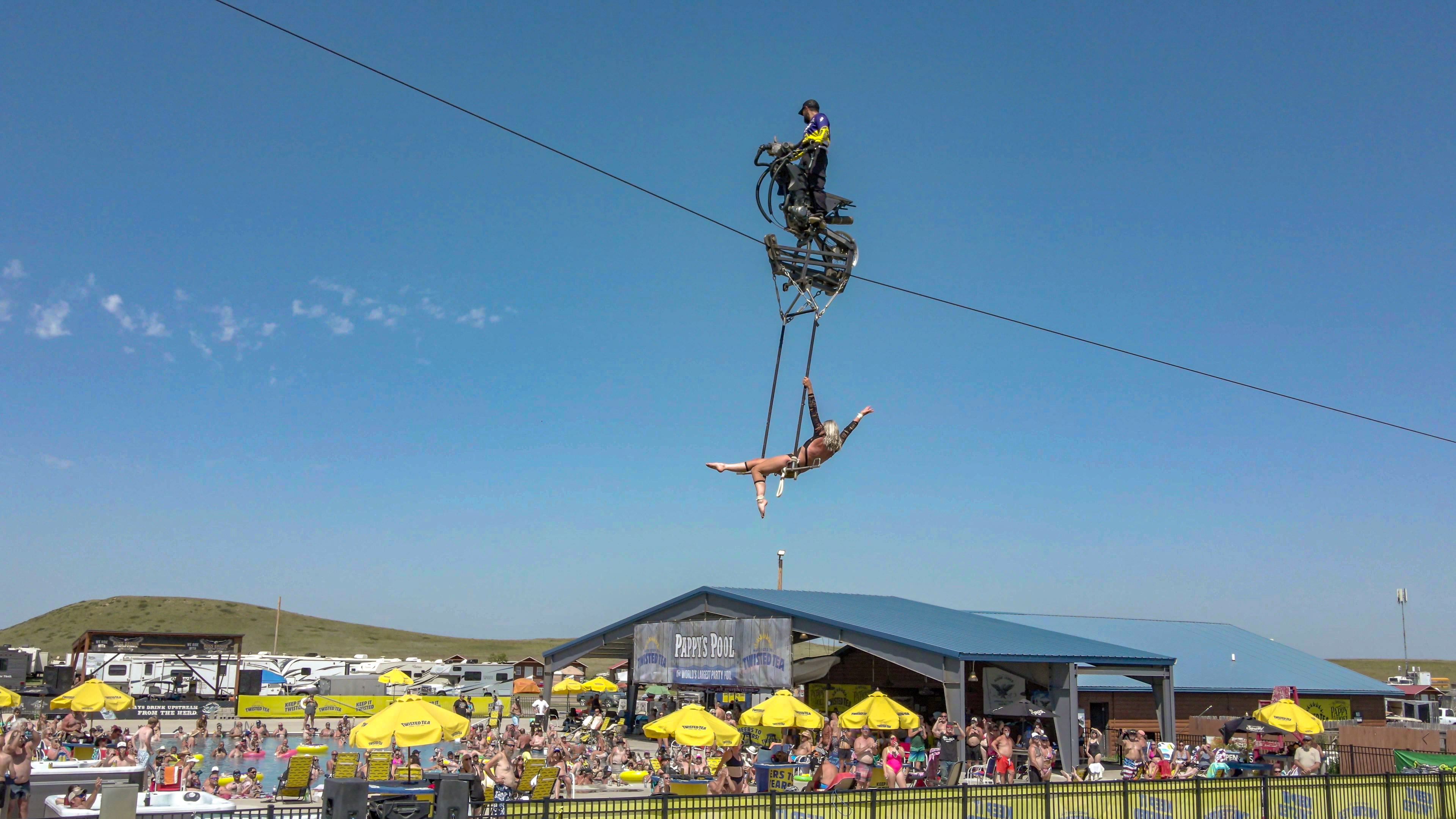 Highwire motorcycle performers perform aat Pappy Hoel campground world's largest party pool for Sturgis Motorcycle Rally interior with boat hanging from the rafters