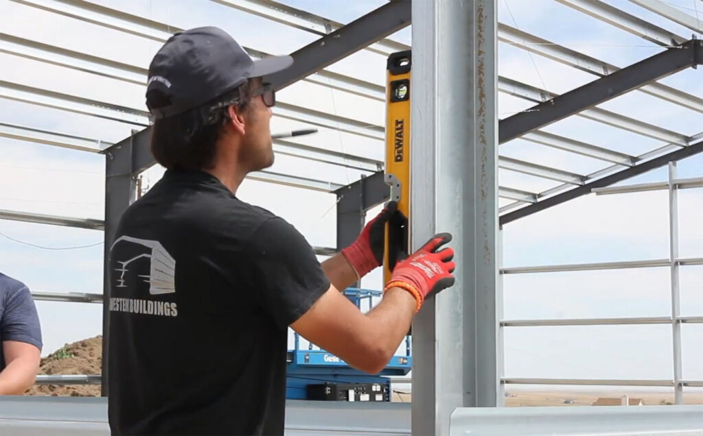 Great Western Buildings founder Eric Beavers checking a building frame for straight and plumb readings before installing personnel door